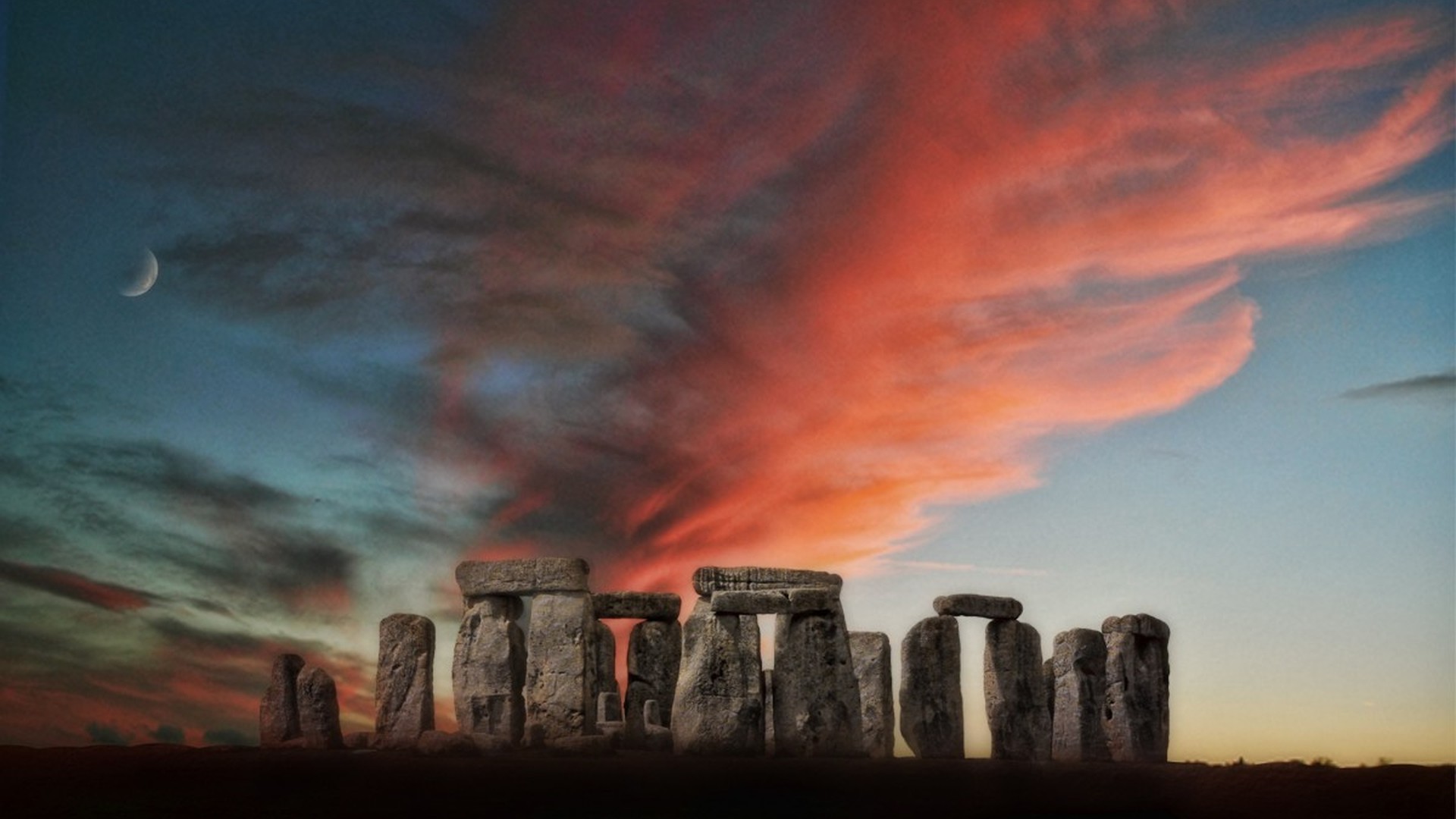 Stonehenge silhouetted under a vivid dawn sky with a crescent moon